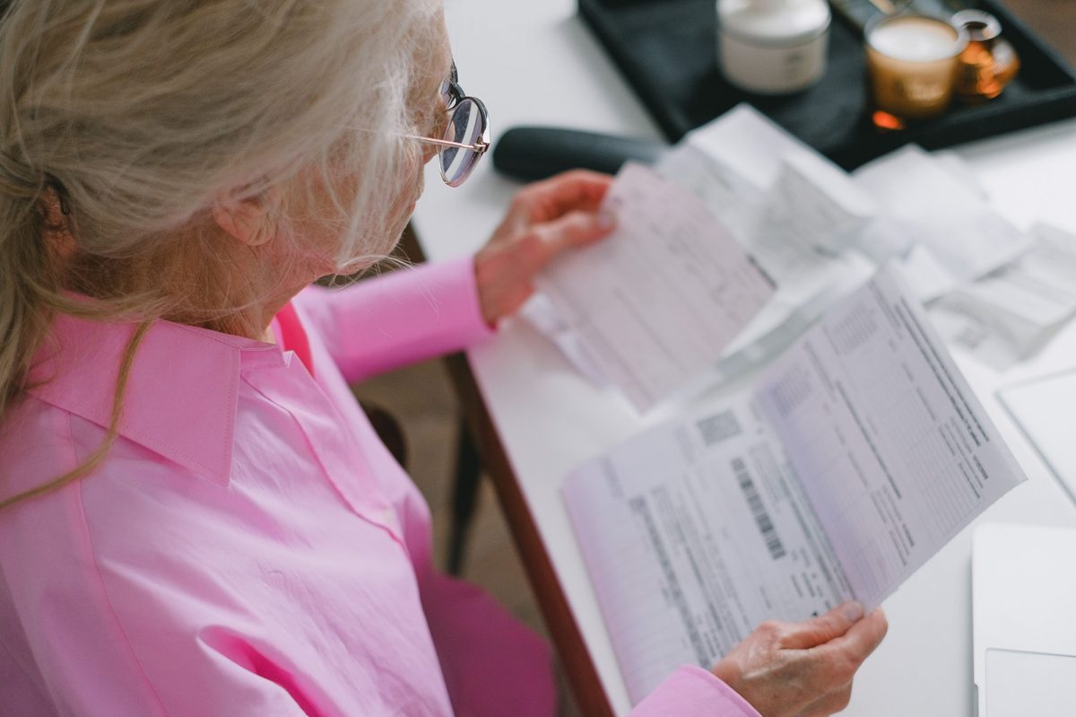 Older woman at her kitchen table going through household bills